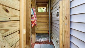 A wooden exterior with a narrow entrance, a small step, and a metal door handle. - The Sand-Bar (Carolina Beach)
