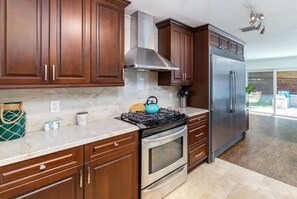 Fully equipped kitchen with gas stove, refrigerator, and range hood.