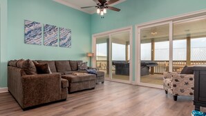 A spacious living area with a brown sectional sofa, a patterned armchair, and a ceiling fan.