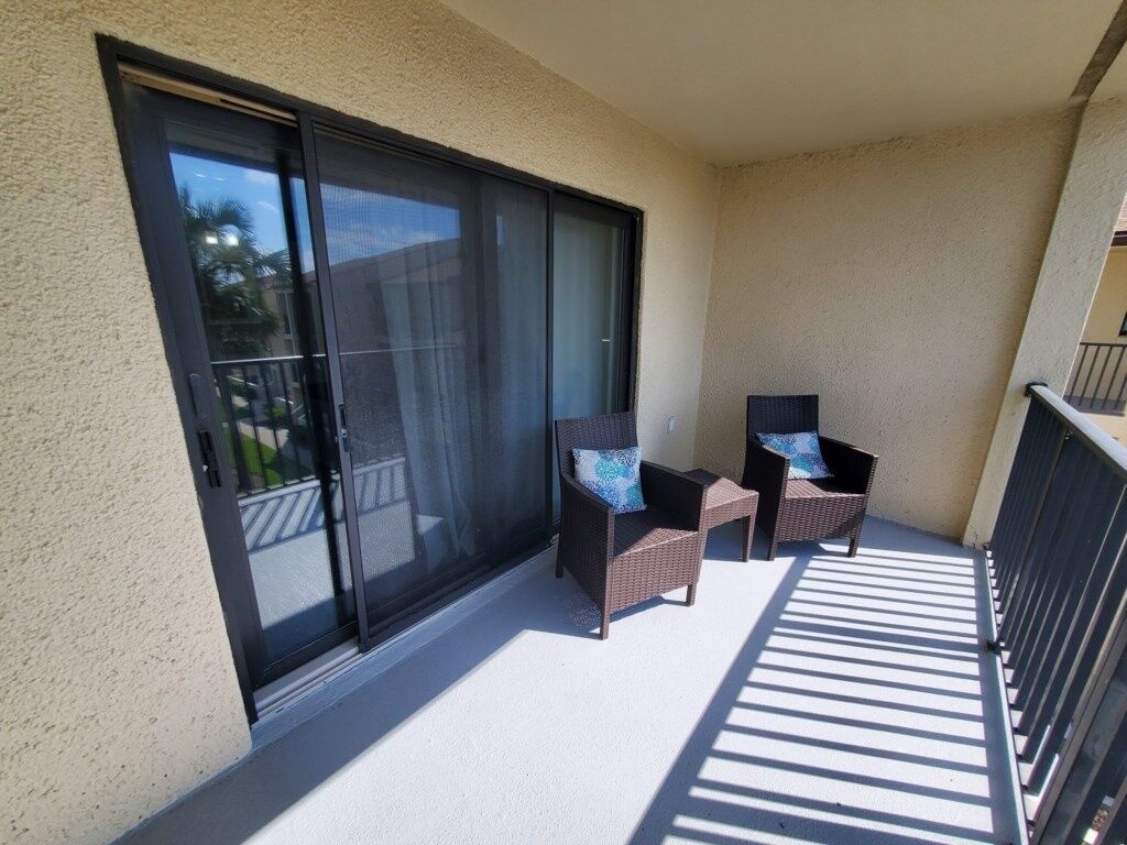 A balcony with two wicker chairs and a sliding glass door.