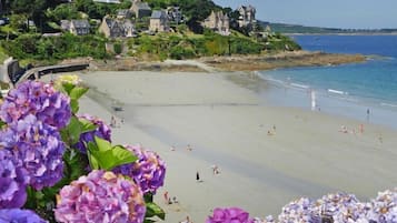 Una playa con gente nadando y tomando el sol, rodeada de casas y vegetación.