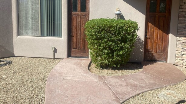 A building with a large window, two wooden doors, and a well-maintained hedge. - This casita is located in the Estrella neighborhood and boasts amazing View’s.  (Goodyear)