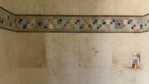 A bathroom with a bathtub, a shower, and a small shelf with a bottle. - This casita is located in the Estrella neighborhood and boasts amazing View’s.  (Goodyear)