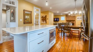 Cocina con una isla blanca, electrodomésticos de acero inoxidable y suelo de madera.