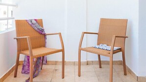 Two wicker chairs with cushions, a white wall, and a blue circular object on the wall. - Narcissos 'Nissi Beach' Apartment E9 (Ayia Napa)