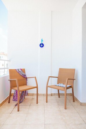 Two wicker chairs with cushions, a white wall, and a blue circular object on the wall.