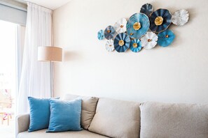 A living room with a beige sofa, two blue pillows, and a wall art piece.