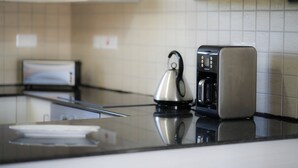 A modern kitchen with a stainless steel kettle, a coffee maker, and a toaster on the counter. - Narcissos 'Nissi Beach' Apartment E9 (Ayia Napa)