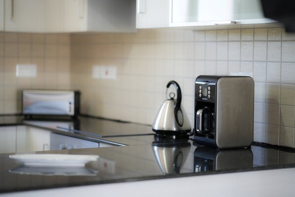 A modern kitchen with a stainless steel kettle, a coffee maker, and a toaster on the counter. - Narcissos 'Nissi Beach' Apartment E9 (Ayia Napa)