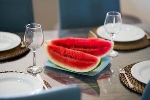 A dining table with plates, cutlery, and a slice of watermelon.