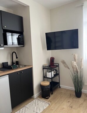 Kitchen features a microwave and oven, coffee maker, and kettle, along with a large flat-screen TV.