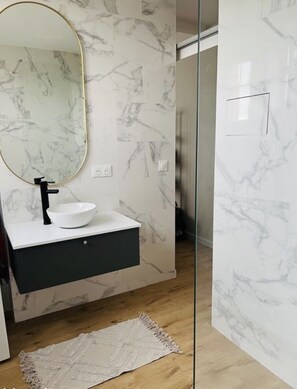 Bathroom features a sink, large mirror, and dark-colored vanity.