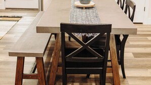 Un comedor con una mesa rectangular, cuatro sillas, un banco y una planta en maceta.