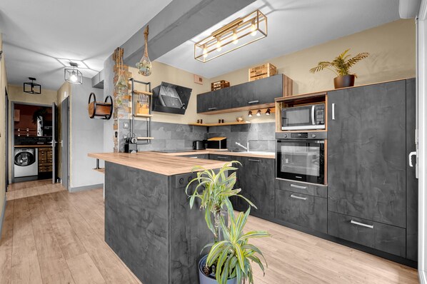 Eine moderne Küche mit dunklen Schränken, einer Kochinsel aus Holz und eingebauten Geräten.