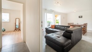 En moderne stue med en modulsofa, et spejl med træramme og et spiseområde med et bord og stole.