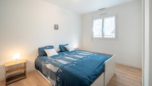 Et soveværelse med seng, natbord, vindue og loftslampe.