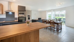 Et moderne køkken med en træø, indbyggede hårde hvidevarer og et spiseområde med bord og stole.
