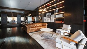Un vestíbulo moderno con un sofá de cuero, sillones blancos y una mesa de centro de mármol.
