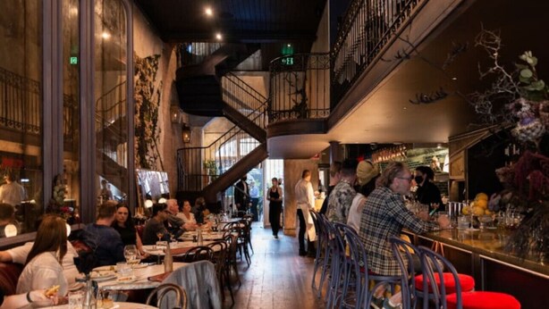 Un restaurante con varias mesas, una escalera central y una zona de bar.