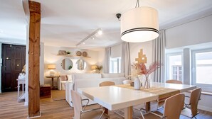 Un comedor moderno con una mesa blanca, sillas de madera y una lámpara colgante.