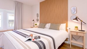 Un dormitorio ordenado con una cama grande, mesitas de noche, un espejo y un reloj de pared.