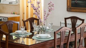 A dining table set with glassware and plates, surrounded by wooden chairs. - Deluxe 2 Bedroom apt in Petroupoli (Petroupoli)