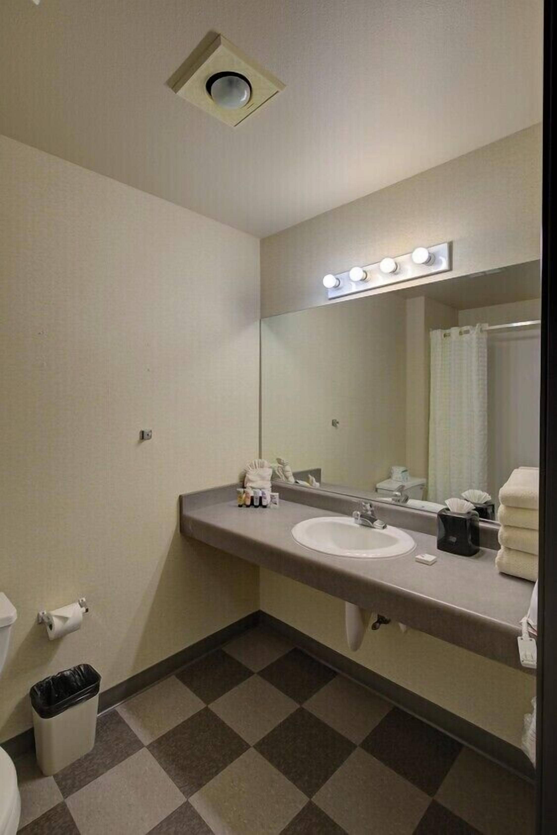 Un baño con lavamanos, espejo e iluminación superior.