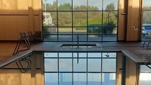Una piscina interior con vistas a un bosque a través de amplias ventanas.