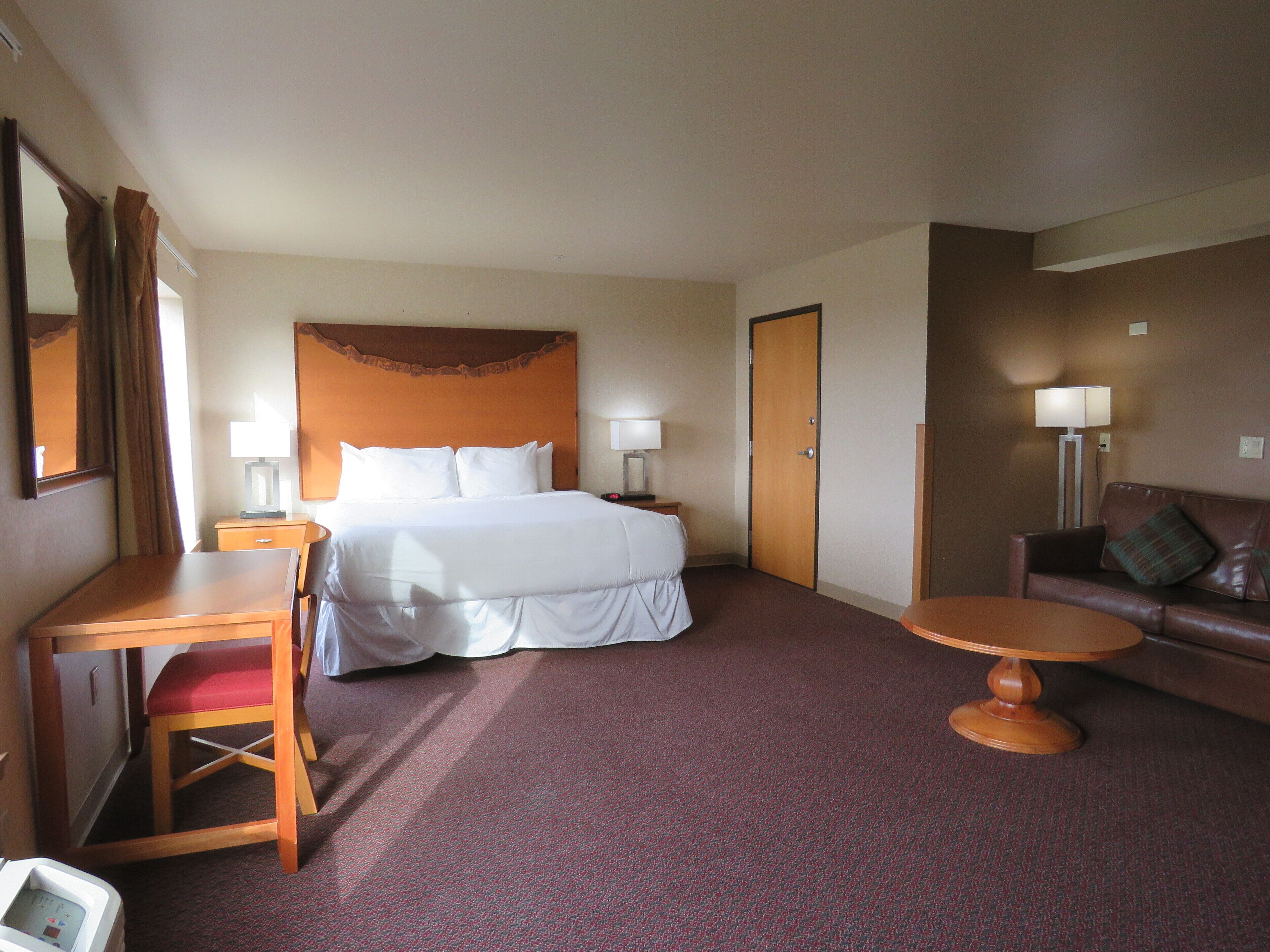 A hotel room with a bed, a desk, a chair, a sofa, and a small table.