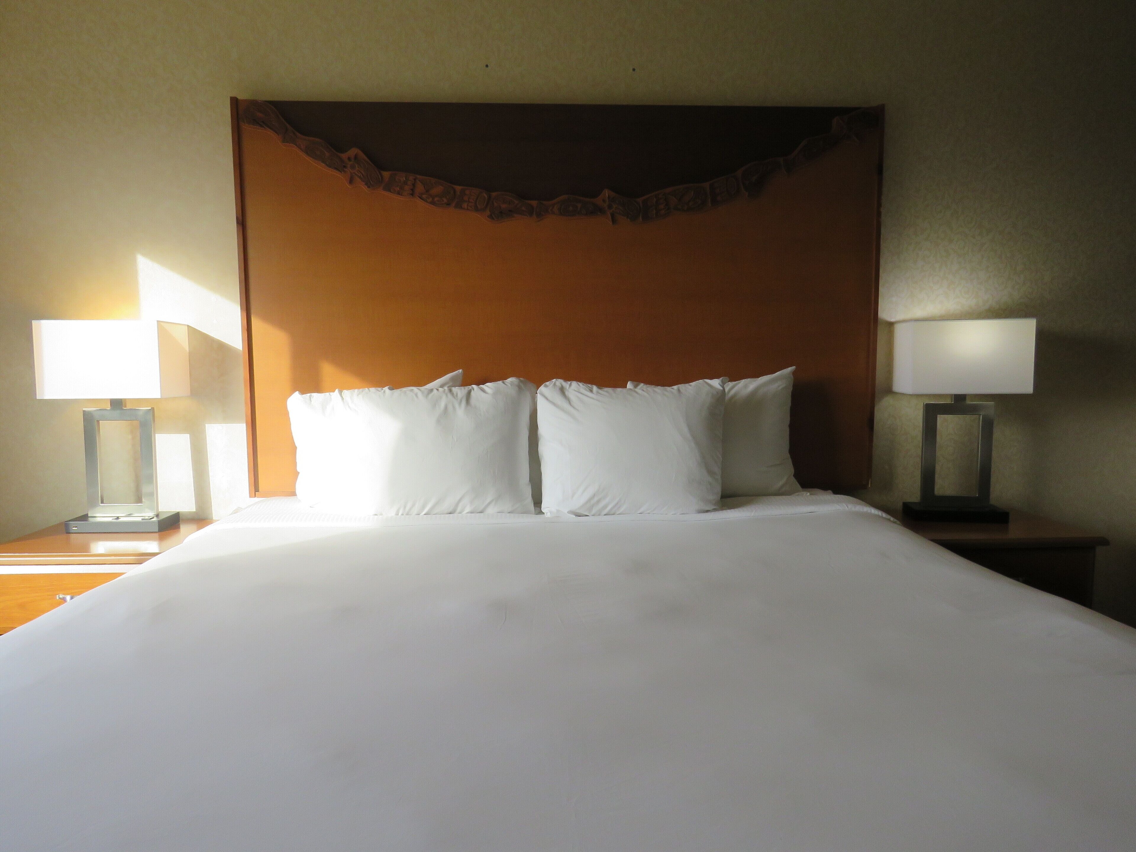 A hotel room with a large bed, two bedside tables with lamps, and a decorative headboard.