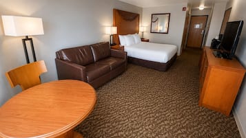 Una habitación de hotel con cama, sofá, escritorio, silla y mesa.