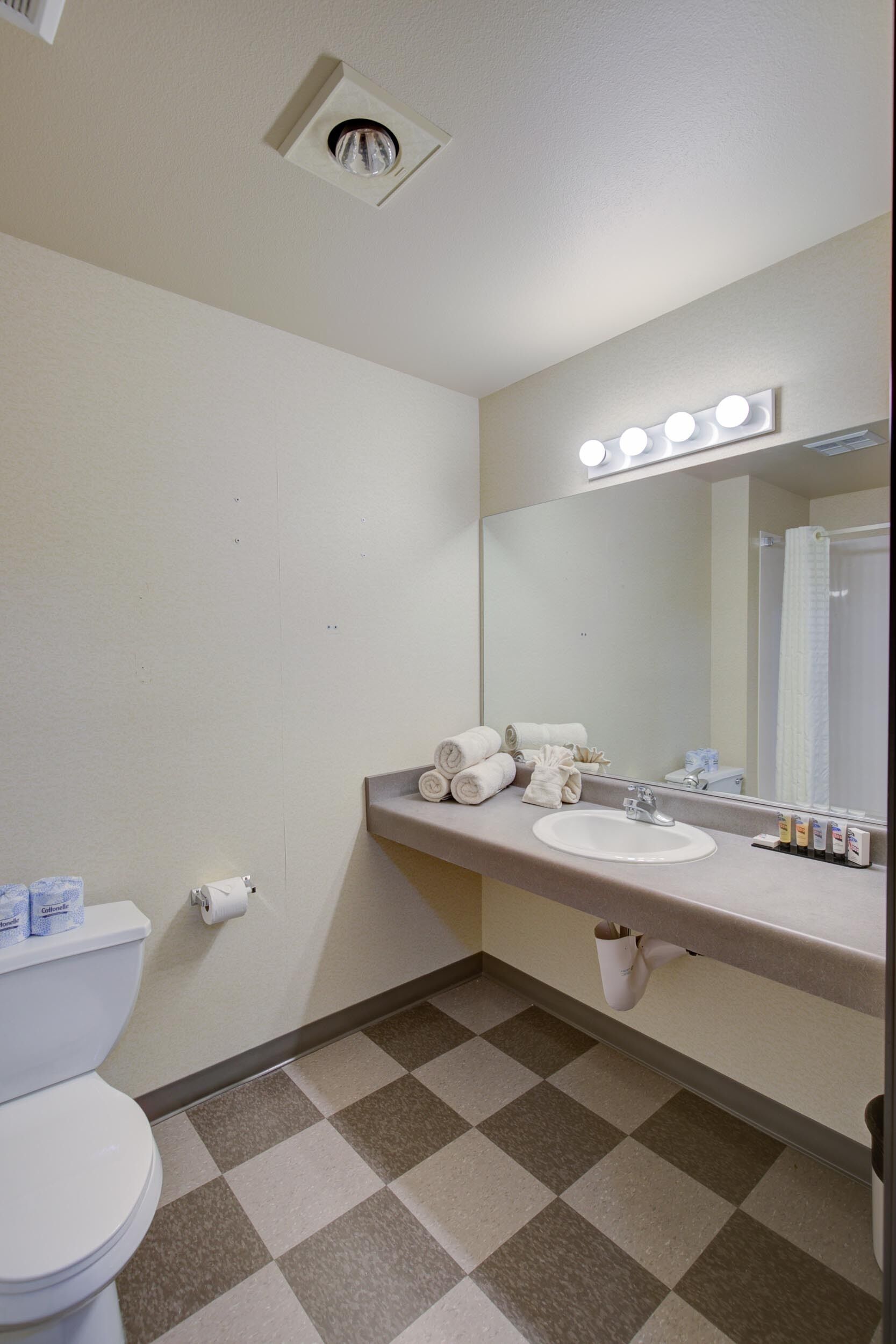 A bathroom with a white sink, mirror, and a ceiling light fixture.