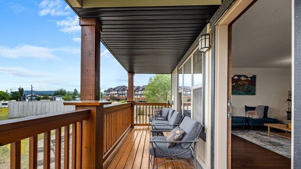 Una terraza de madera con mobiliario exterior y vistas a casas al fondo.