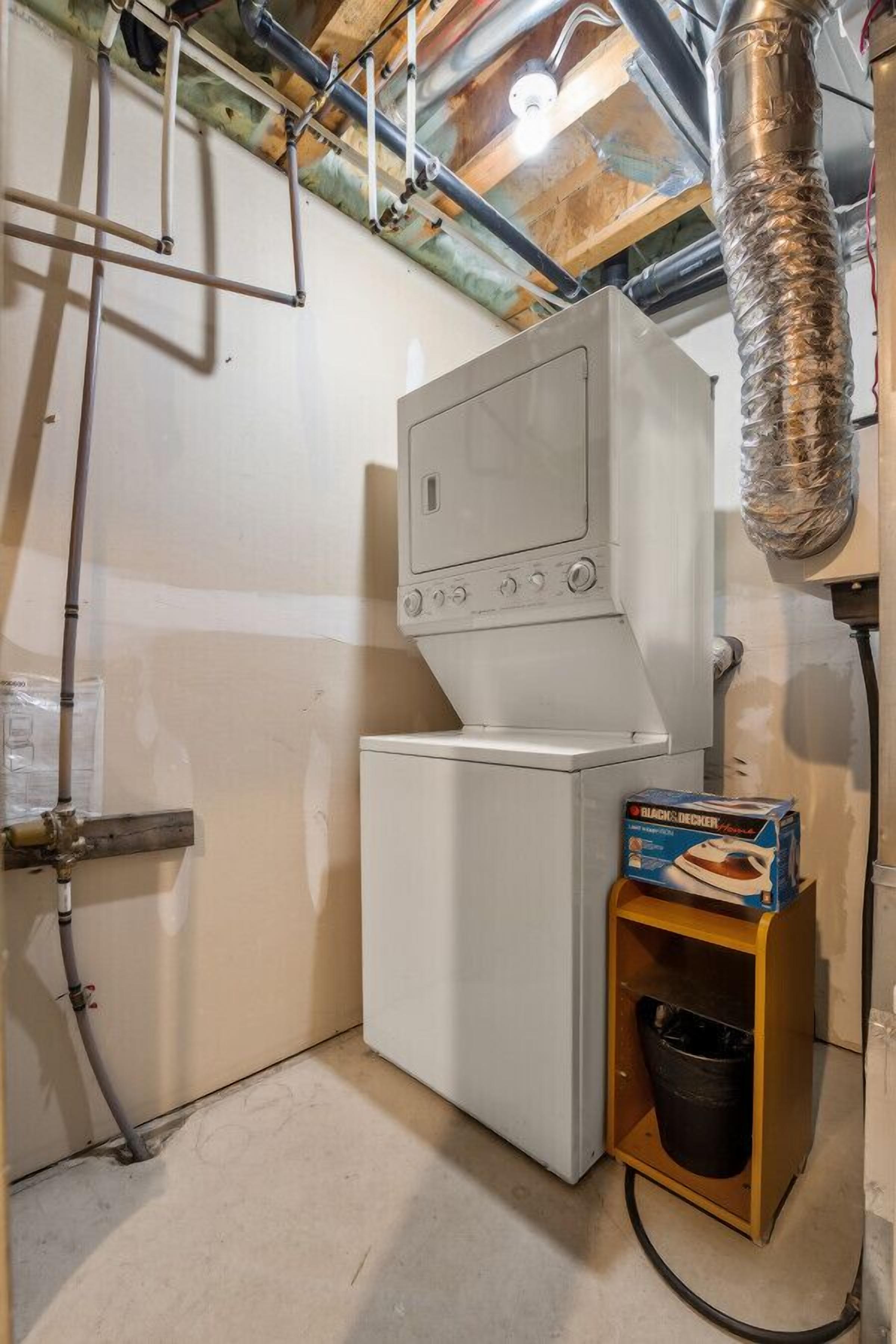 A laundry room with a washing machine and dryer, a water heater, and a box of detergent.