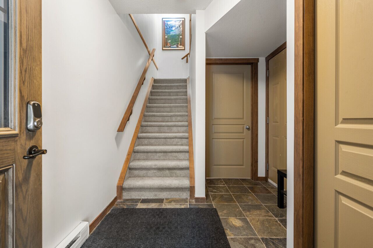 A staircase with wooden handrails and carpeted steps leading to a door.