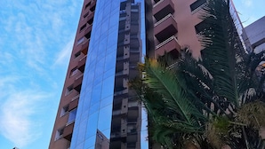 A high-rise building with a glass facade and a white metal structure in front.