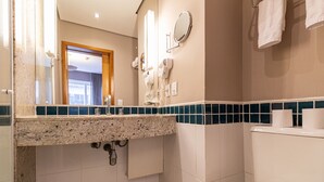 A bathroom with a granite countertop, a mirror, a hairdryer, and a toilet.