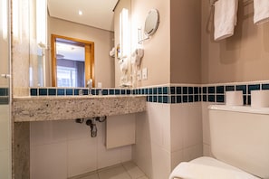 A bathroom with a granite countertop, a mirror, a hairdryer, and a toilet.
