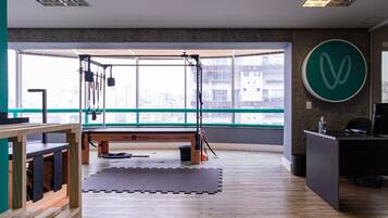 Academia com uma grande janela, piso de madeira e equipamentos de ginástica.