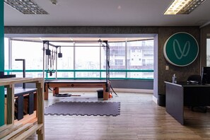 A gym with a large window, wooden floor, and exercise equipment.
