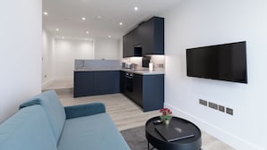 Un salon moderne avec un canapé, une table basse et un téléviseur à écran plat fixé au mur.