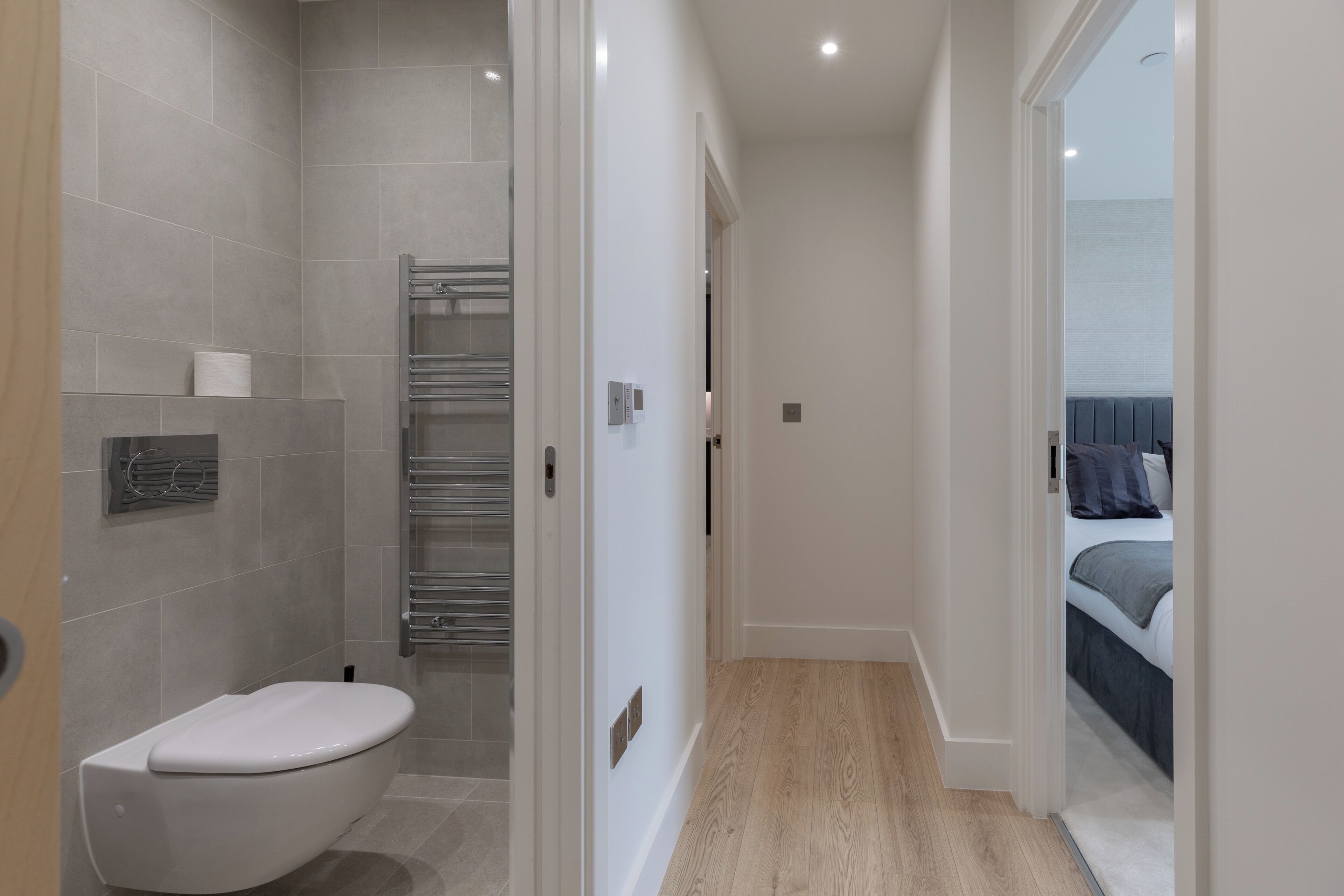 A modern bathroom with a toilet, shower, and a towel rack.