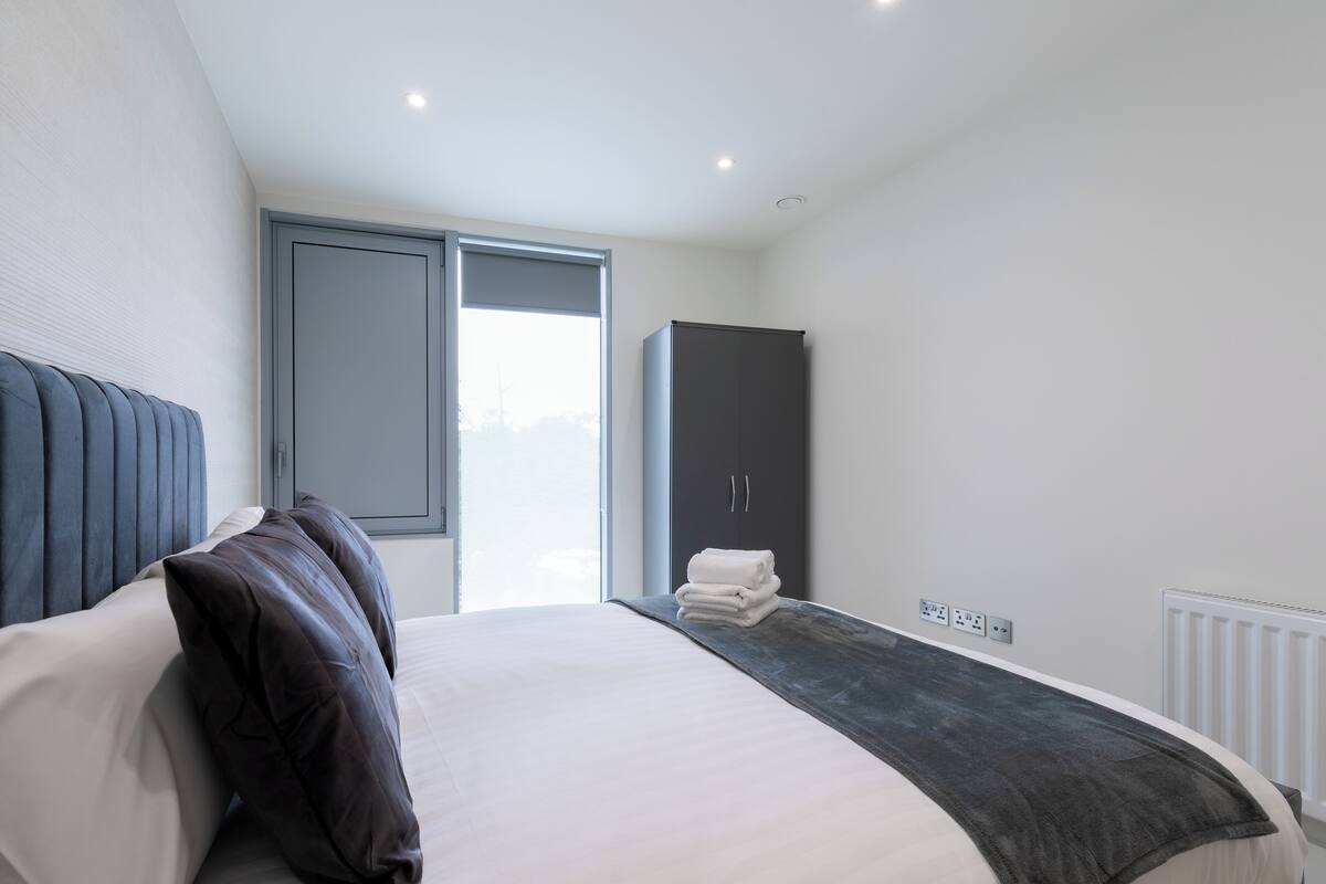 A modern bedroom with a large bed, a wardrobe, and a window.