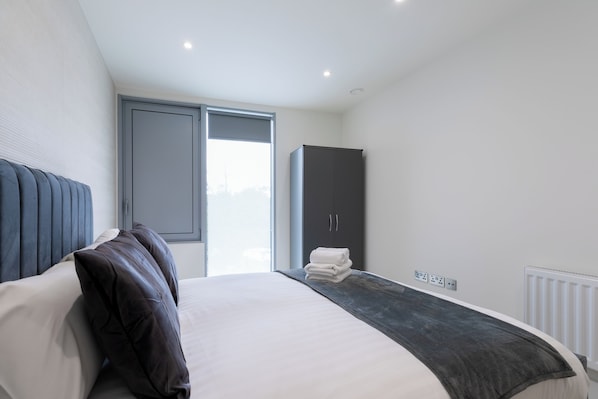 Une chambre à coucher moderne avec un grand lit, une armoire et une fenêtre.