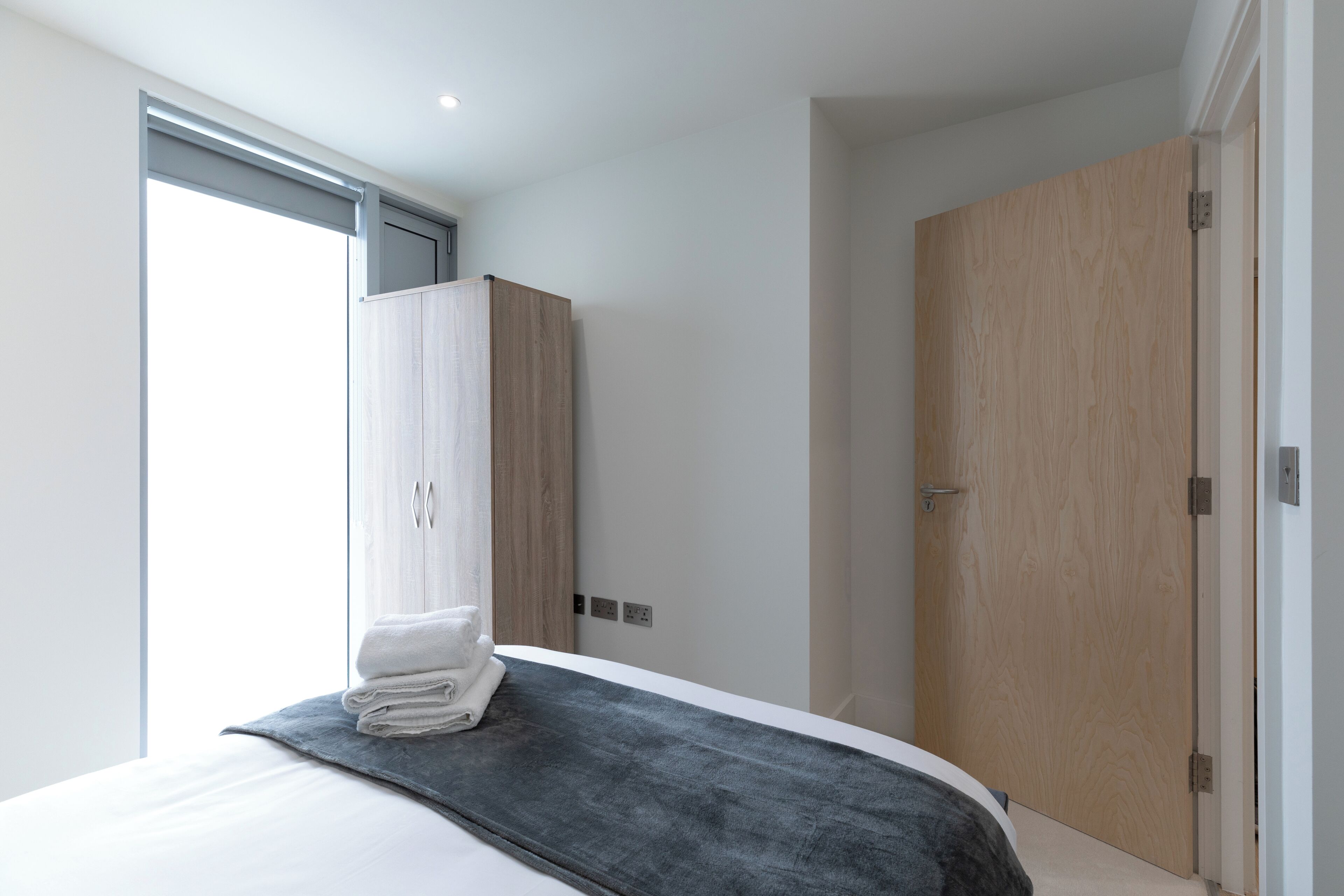 A modern bedroom with a large bed, a wardrobe, and a door.