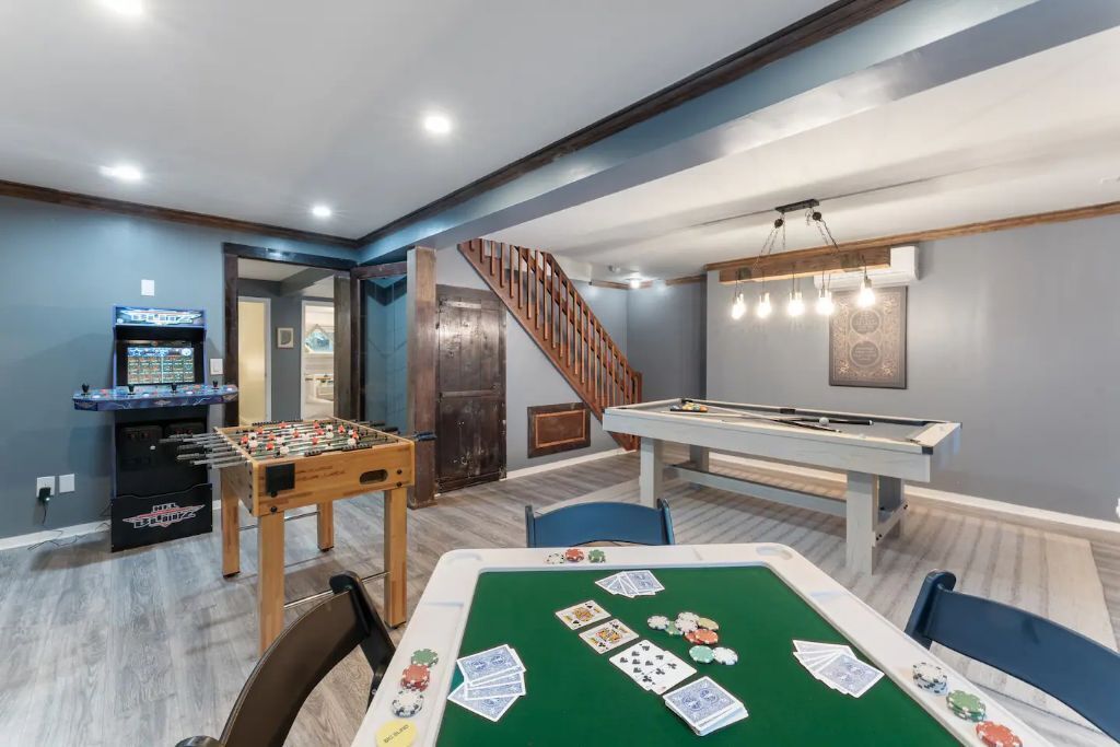 A room with a pool table, foosball table, and a dartboard.