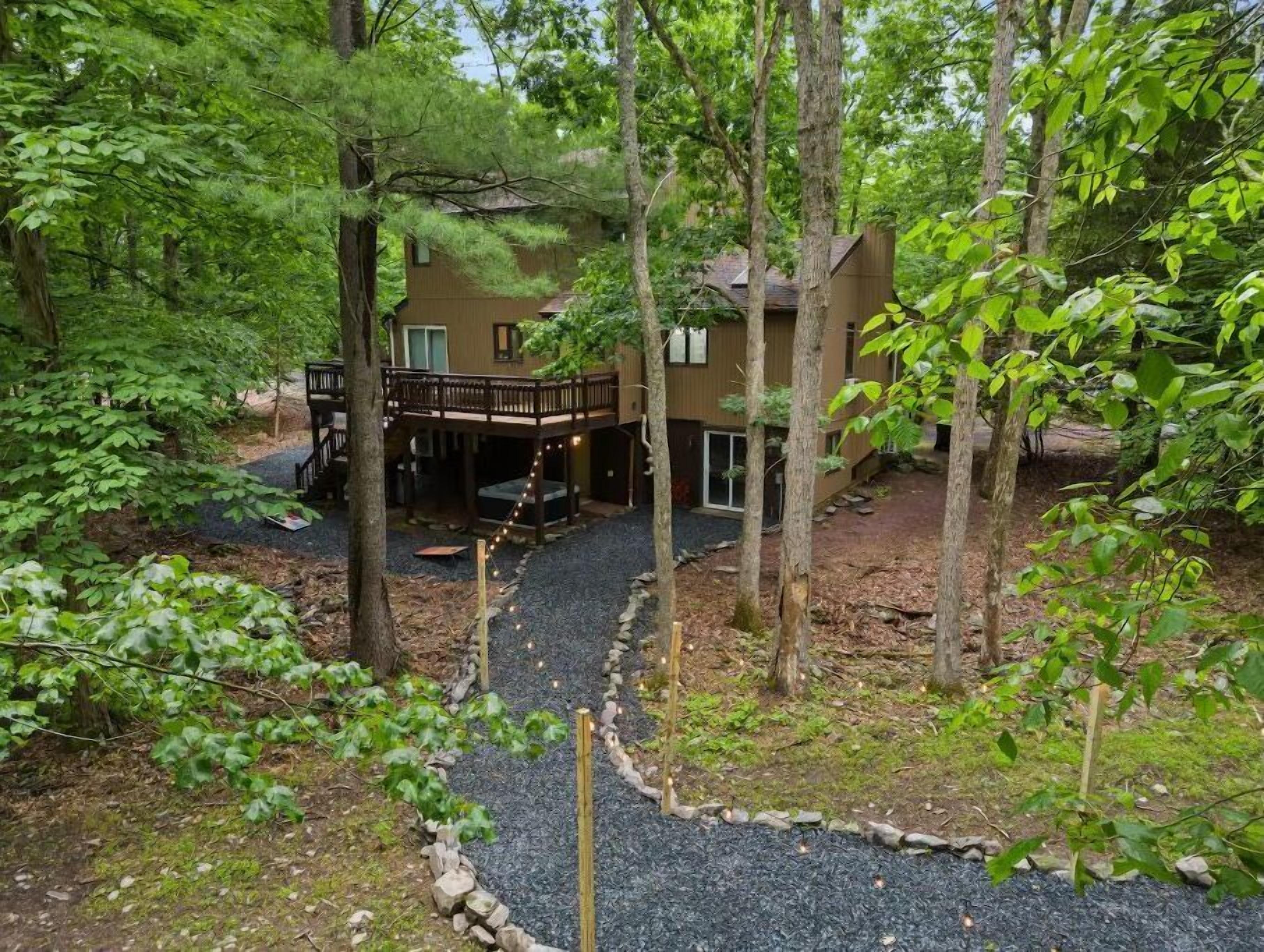 A cabin with a deck and a covered outdoor area, surrounded by trees.