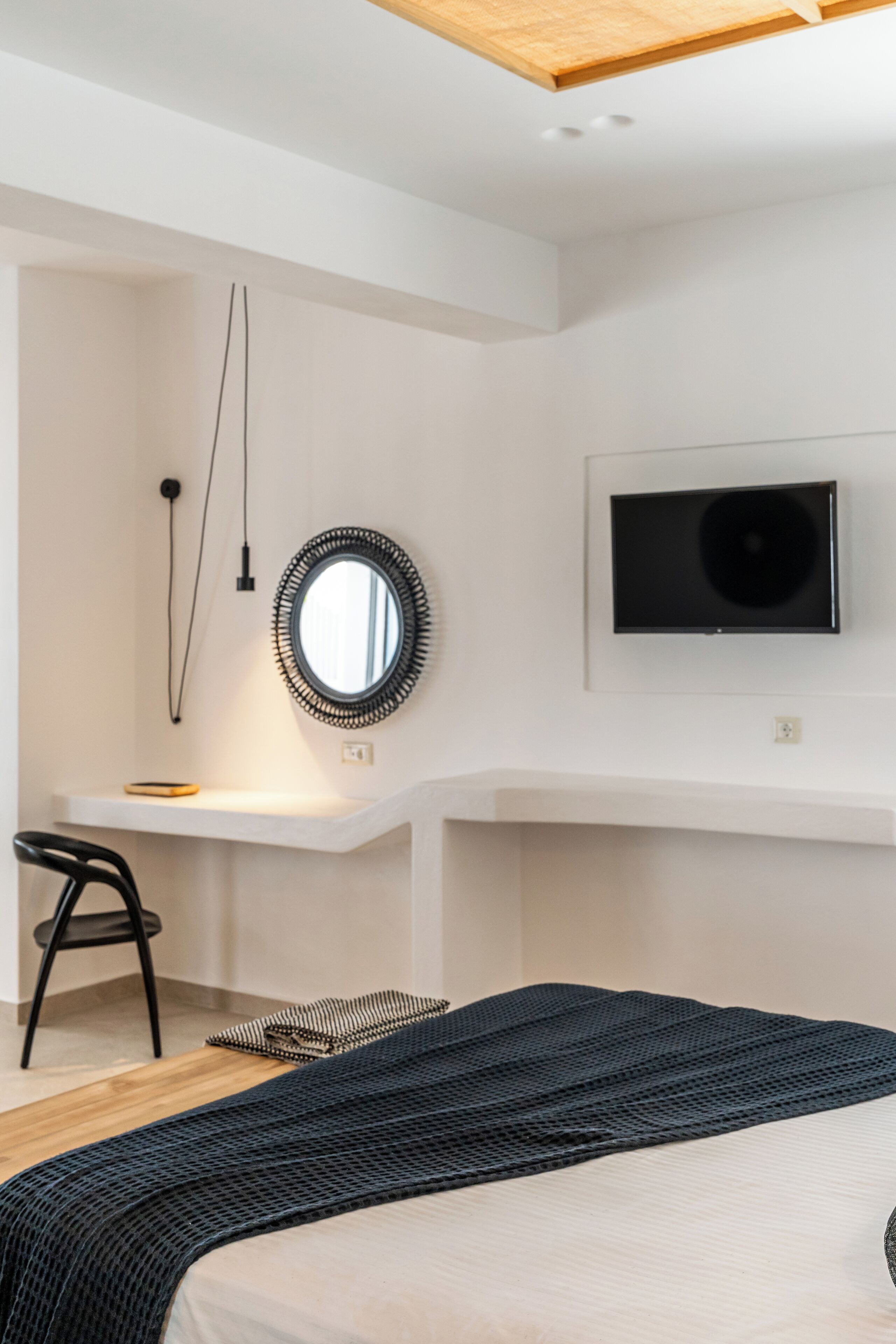 Une chambre à coucher moderne avec un lit, un bureau, une chaise, une télévision et un miroir.