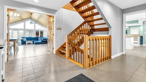 A modern interior with a wooden staircase, a living area with a blue sofa, and a kitchen area.