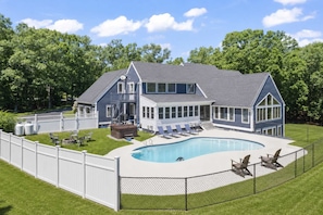 A two-story house with a swimming pool, a fenced backyard, and a covered patio area.